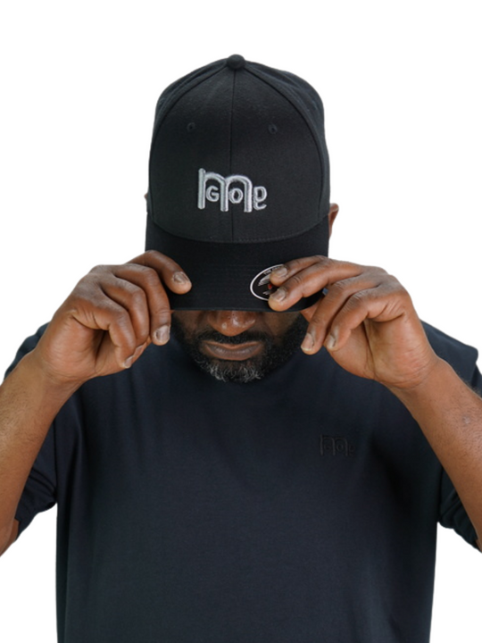 Smooth and sleek Black 6 panel Fitted Hat has curved Silver under visor with puff style GODinme logo embroidered in Grey on front and flat style GODinme name embroidered on back.